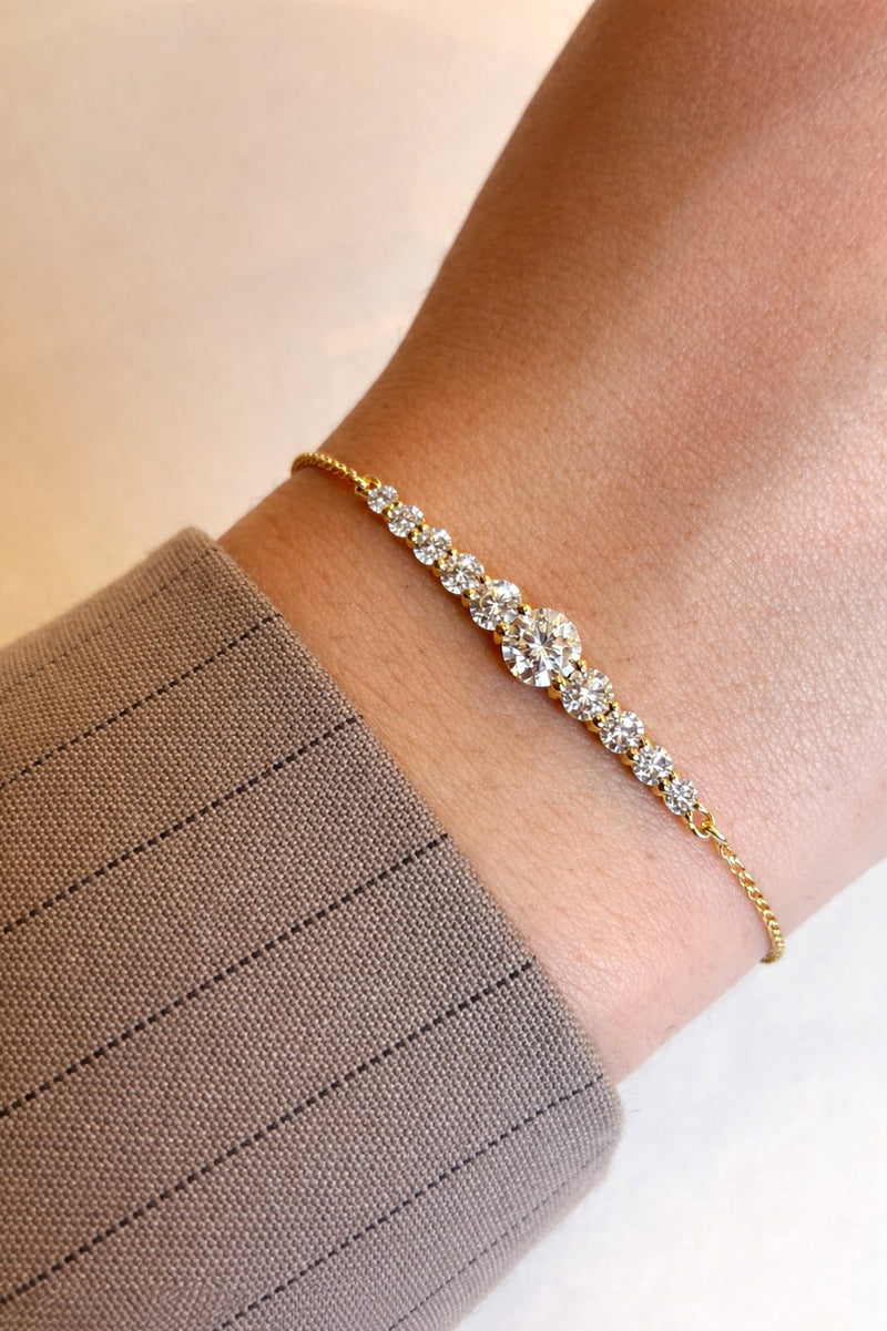 Gold bracelet with clear stones on a wrist against a neutral background